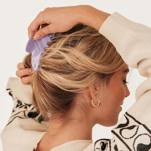 Close-up van een model met blond haar en een haarklem in de kleur Hazy Lilac.